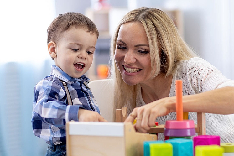 Junge Frau und Sohn spielen im Mutter Kind Heim